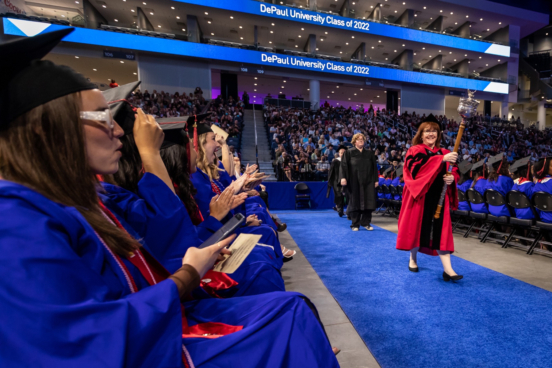 Marie Donovan, associate professor in the College of Education, holding the university mace, lead the procession at the College of Education/College of Communication ceremony.